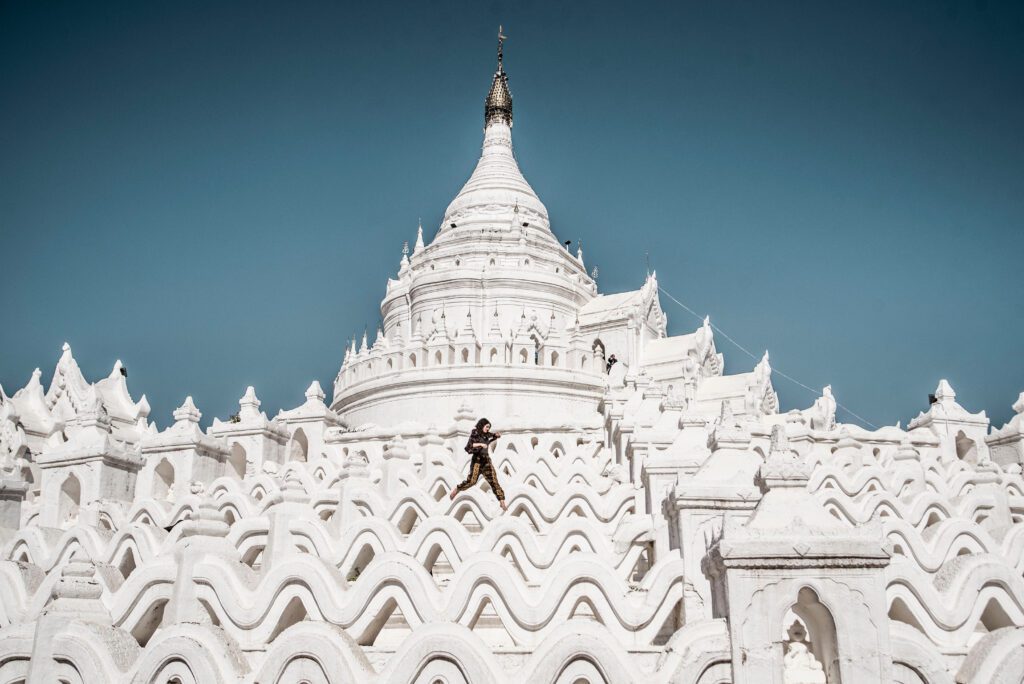 A person is jumping in the air over a white building.