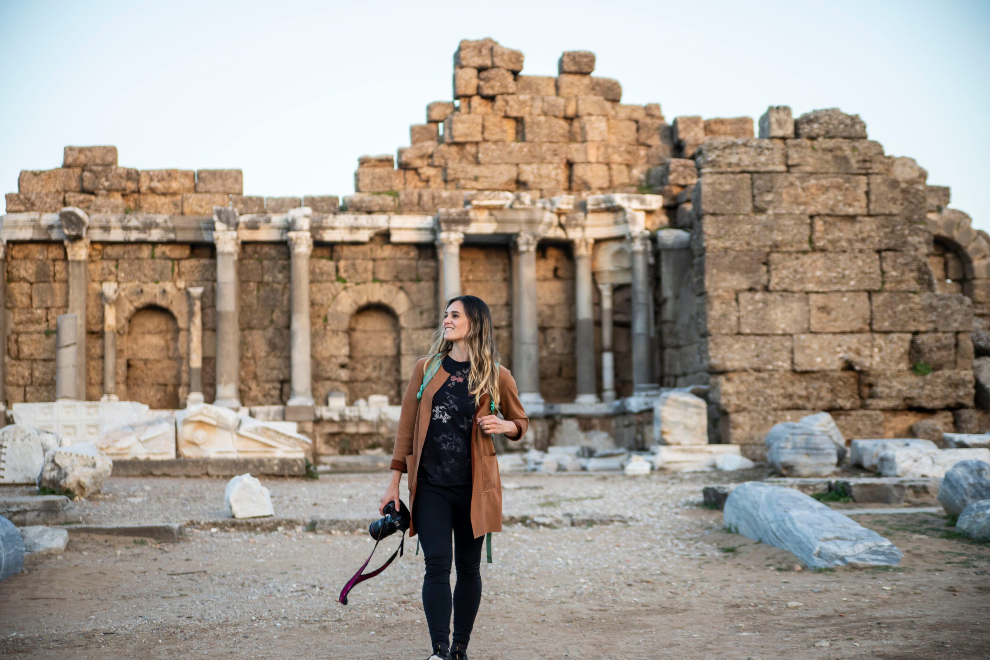 female traveler photographer walking through roan ruins in turkey A woman standing in front of an old building.