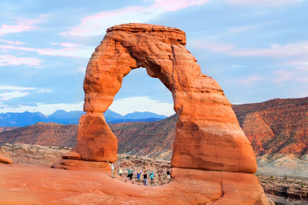 A group of people (two families with children) joined hands and raised them. Arches National Park, Utah