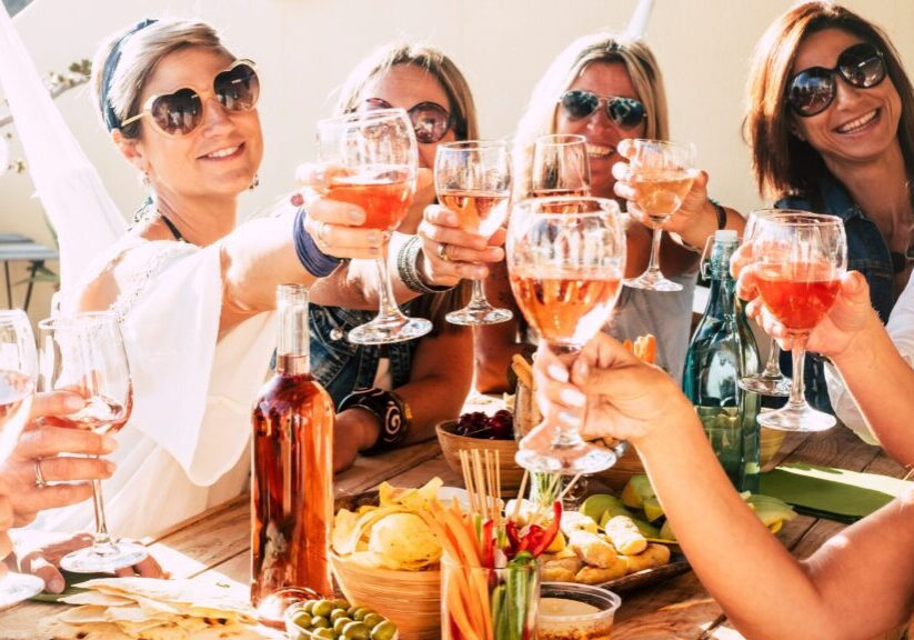 Cheerful group of happy female people clinking and toasting together with friendship and happiness - young and adult women have fun eating - food and beverage celebration concept Women toasting with ros wine outdoors.