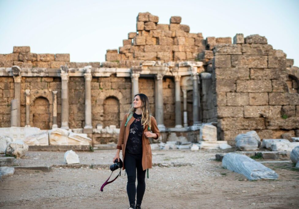female traveler photographer walking through roan ruins in turkey A woman standing in front of an old building.